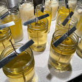 freshly poured soy candles in clear jars in various stages of curing