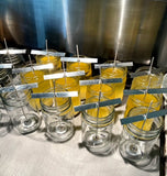 Jars with yellow liquid and metal straws on a metallic surface