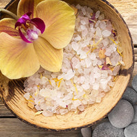 wood bowl filled with sea salt and a yellow orchid on the side