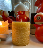 lit beeswax candle burning and unlit fleur di lis molded beeswax candle