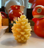 beeswax candle shaped like a pine cone on a shelf